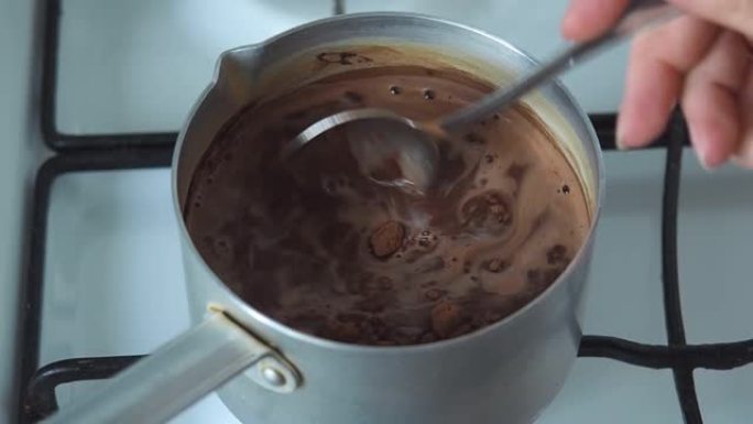 用勺子在铝勺中烹饪和混合热可可巧克力。在煤气炉上酿造热巧克力饮料。