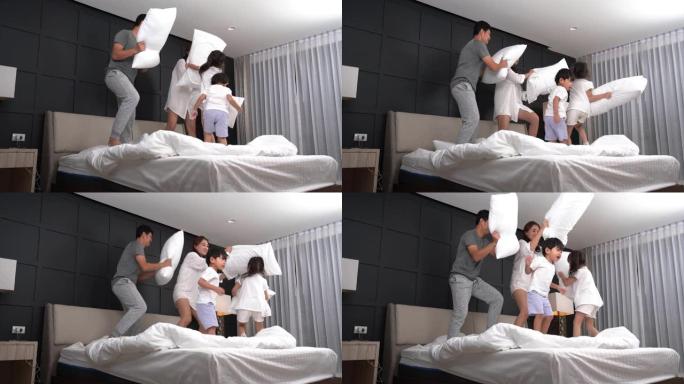 视频系列快乐的亚洲年轻父母殴打躺在床上的小孩，枕头在卧室里一起玩。