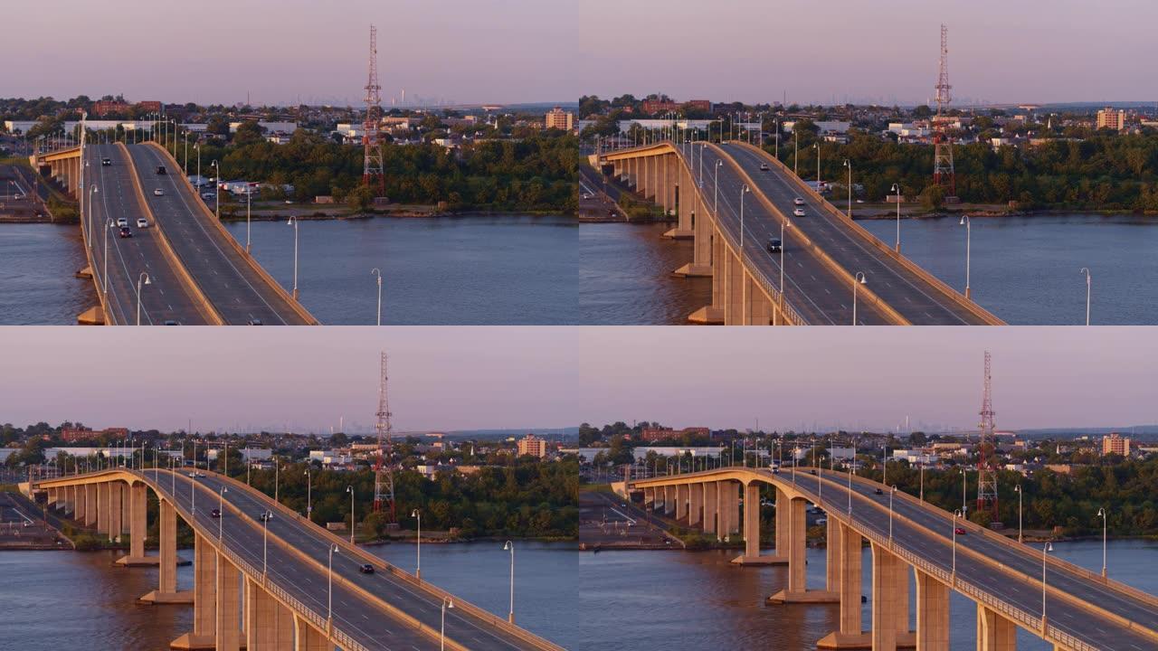 日落前的傍晚，在新泽西州拉里坦河上的胜利桥上鸟瞰图，背景是纽约市曼哈顿的遥远景色。平移摄像机运动的视