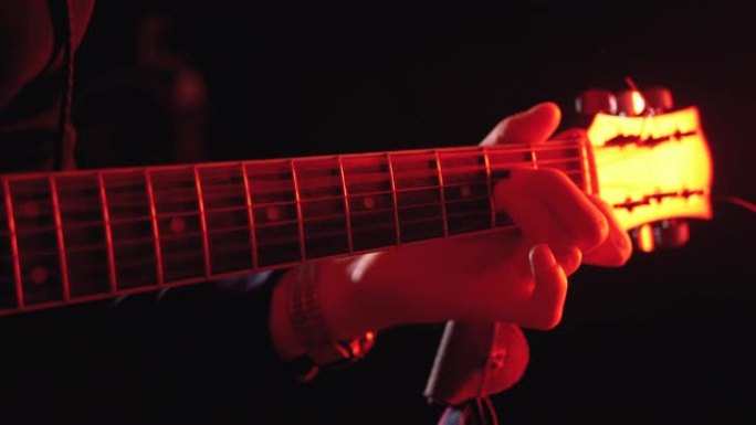 演奏红色背光和黑色背景的原声吉他