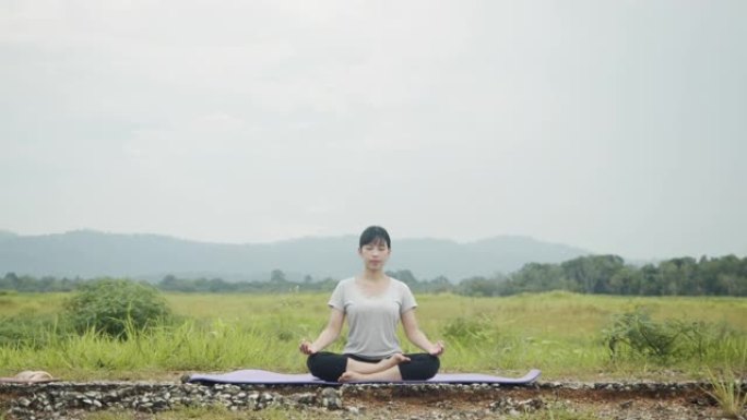 美丽的亚洲高加索女性坐在冥想中，在美丽的山景中摆姿势瑜伽体式平衡。