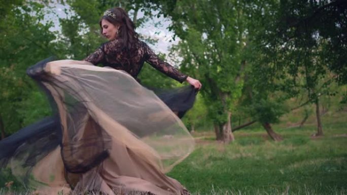 哥特式女王在黑暗的森林中穿着黑色复古飞行连衣裙。织物飘动
