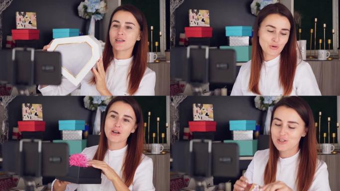 包装礼物的设计师。迷人的女性装饰者进行在线广播，会议，记录视频博客，网络研讨会，站在智能手机前。在线