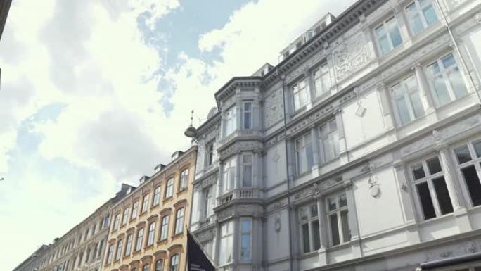 低角度手持视图，走在市场街道上，沿着丹麦哥本哈根的旧建筑
