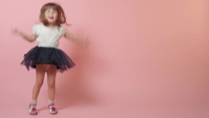 一个可爱的小女孩跳跃着，笑着放纵着。粉色背景。