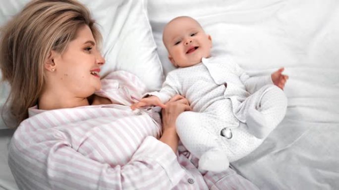 幸福的家庭母亲和可爱的小宝宝享受早晨躺在床上。4k龙红相机