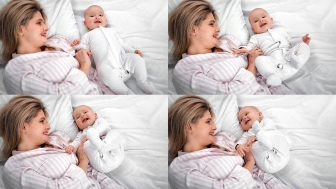 幸福的家庭母亲和可爱的小宝宝享受早晨躺在床上。4k龙红相机