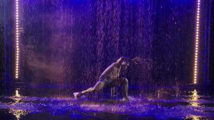 一个运动男子的剪影，展示了卡波耶拉武术在雨水下的蓝光中的技巧。慢动作