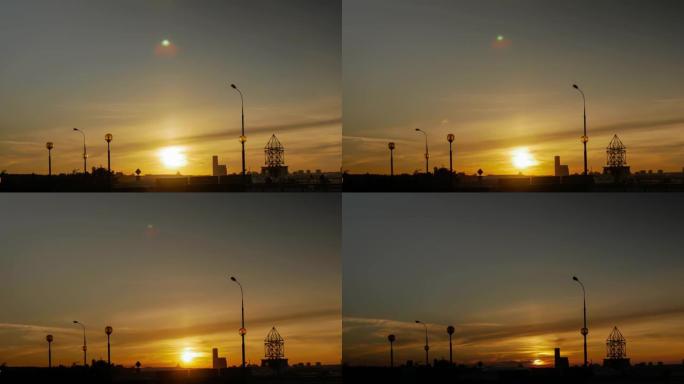 在照亮城市灯笼的轮廓的背景下，城市上空的日落太阳。