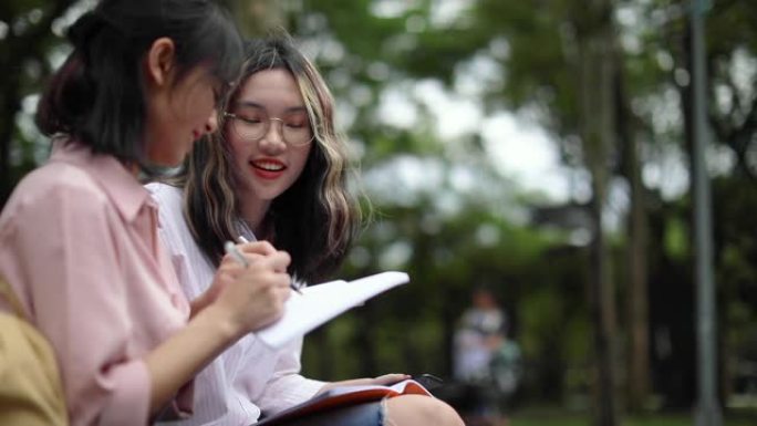 两名年轻亚裔女学生坐在台北公立公园就读