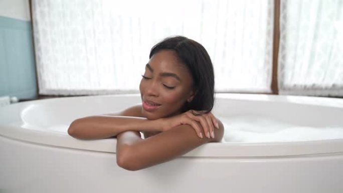 微笑的非裔美国妇女躺在浴室里看着镜头。放松和水疗概念。锅吧。