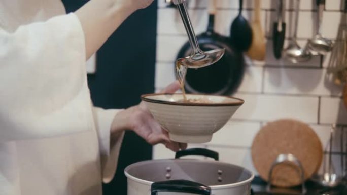 日本妇女将肉汤倒在荞麦荞麦面上