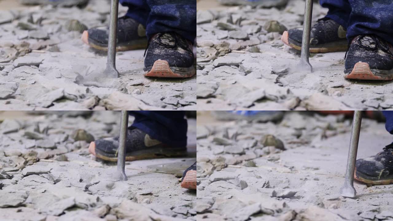 穿着带手提钻的运动鞋的工人在地板上破坏混凝土