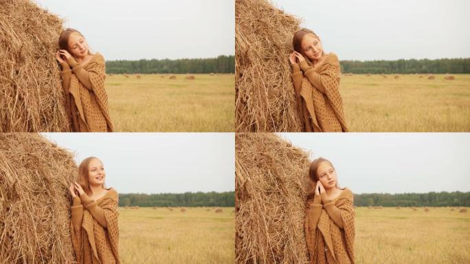 可爱的快乐女孩在田野干草堆附近摆姿势