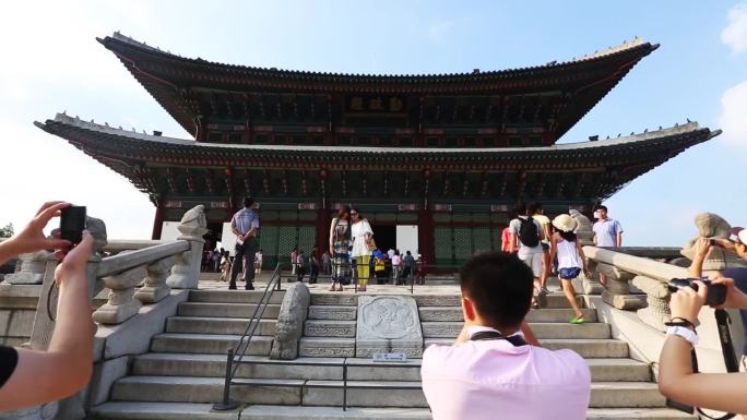 神社前有一盏红灯笼 一张桌子上放着很多食物 人们走在建筑物前的街道上