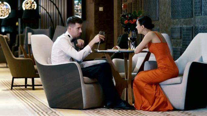 年轻夫妇在现代餐厅约会时聊天和喝白葡萄酒。4K