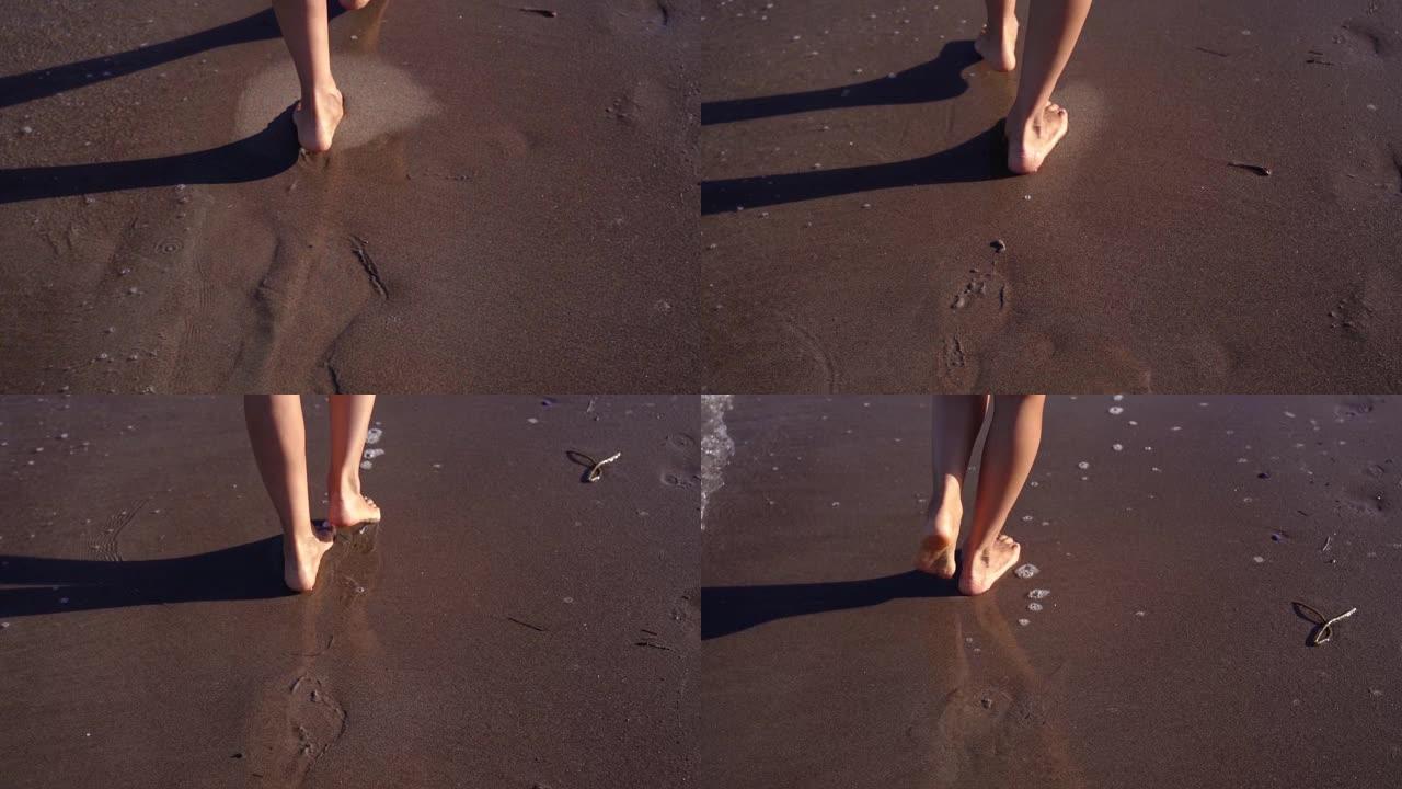 年轻女子的脚沿着海浪边缘附近的湿沙行走