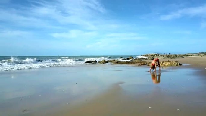 泡沫波在沙滩上滚动，女孩站在瑜伽姿势