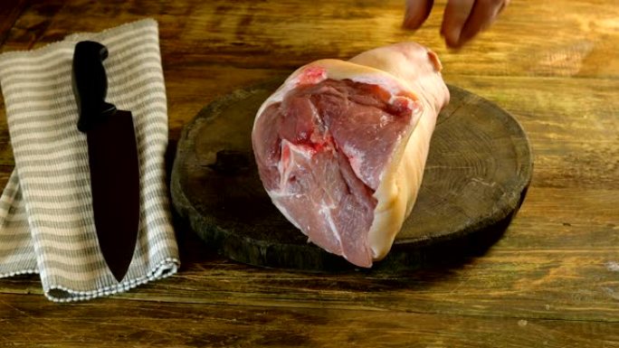 屠夫用钝斧在深色木制桌子上切碎生猪腿。