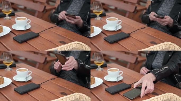 一名妇女将手机连接到移动电源，以便在咖啡馆充电。