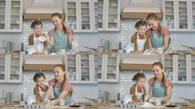 开朗的女孩和妈妈在厨房里扔面粉做面团