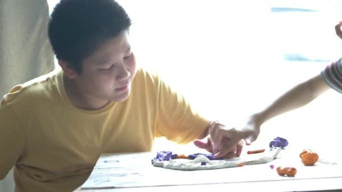 快乐的亚洲男孩在家玩粘土，生活方式概念。