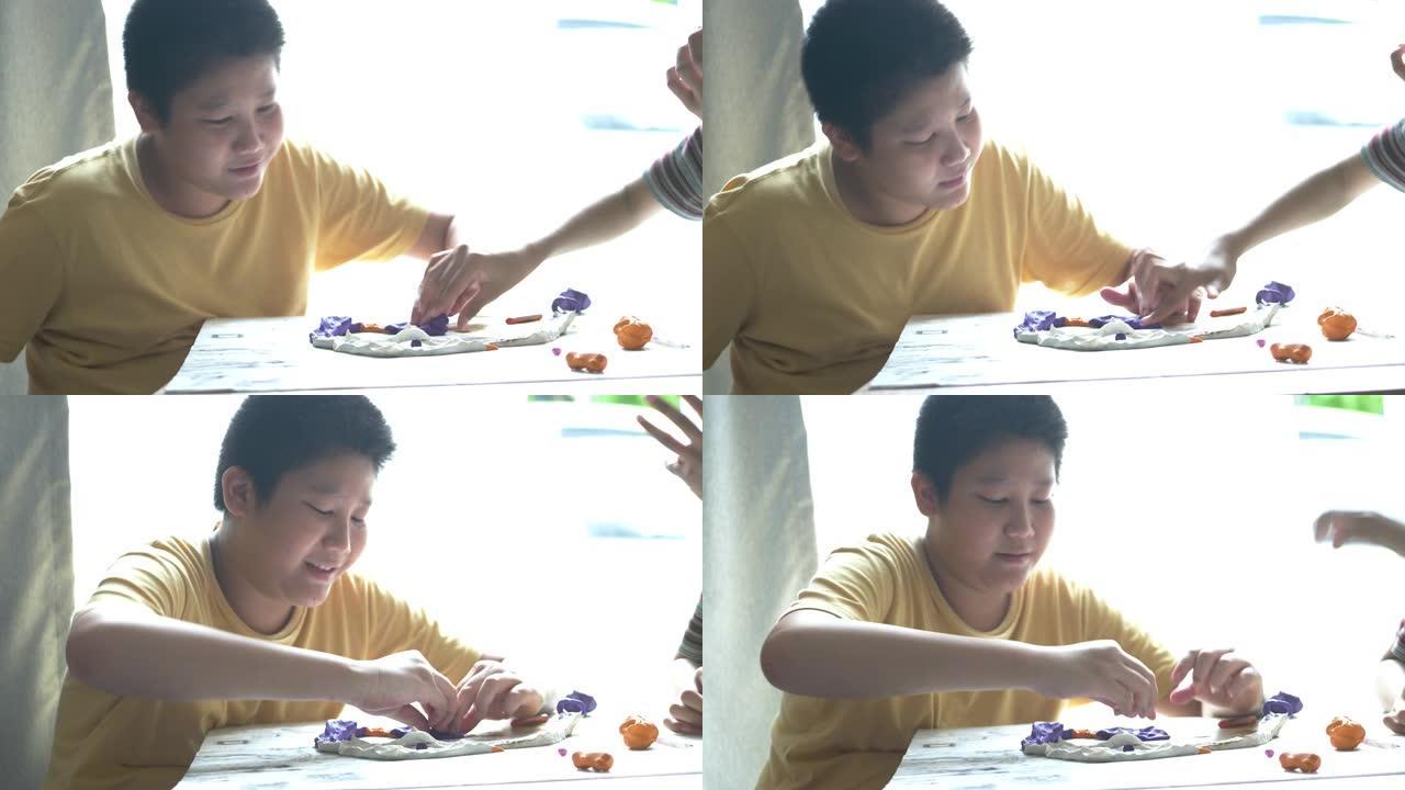 快乐的亚洲男孩在家玩粘土，生活方式概念。
