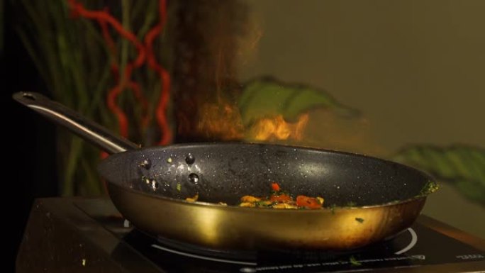 厨师在火上炸蔬菜，将它们扔进煎锅中