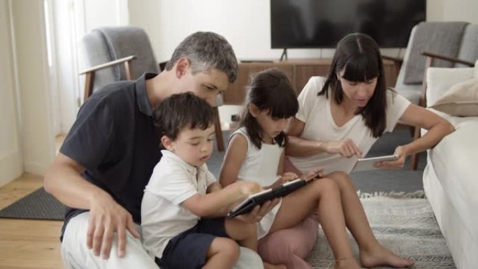 家庭夫妇和两个孩子使用数字平板电脑