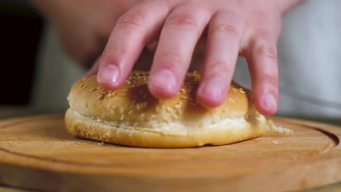 厨房里的厨师用一把大刀将新鲜面包和汉堡包切成两半