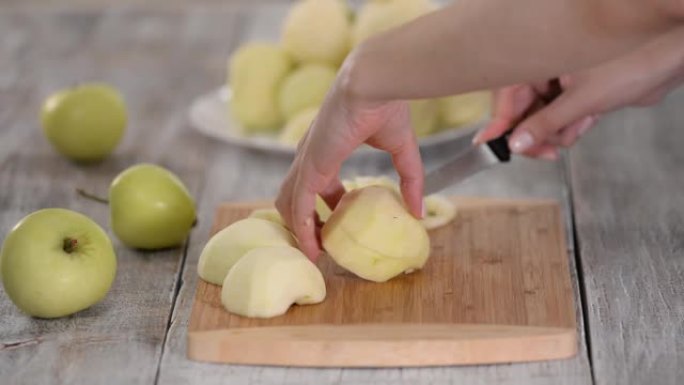 年轻女子的手在木制切板上切苹果