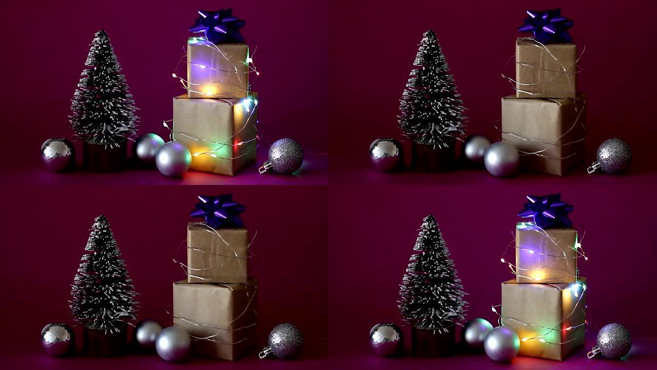 圣诞礼品盒包裹在闪烁的花环中，带有紫色背景上的圣诞树和球。圣诞快乐!假日概念