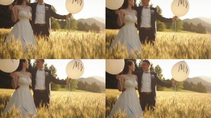 新娘和新郎抱着气球先生和女士站在麦田里