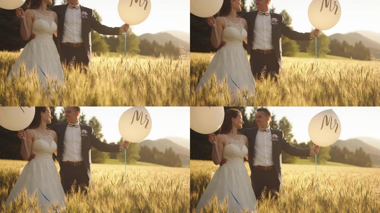 新娘和新郎抱着气球先生和女士站在麦田里
