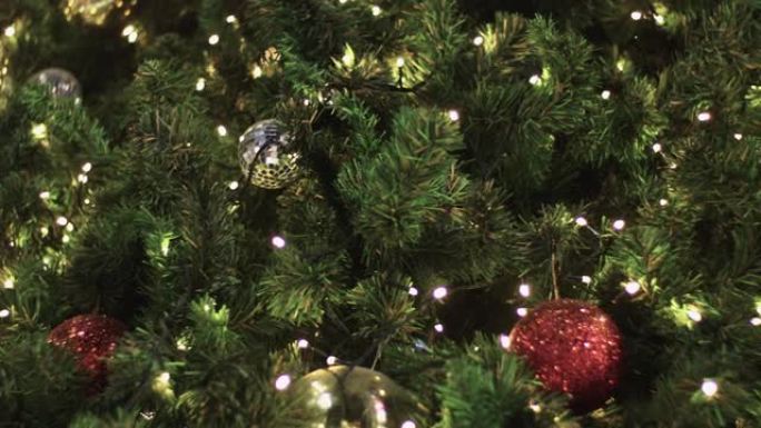 4k特写镜头，悬挂在圣诞树上的金色红球，圣诞节和新年快乐展示，琥珀色暖光，运动镜头，假期装饰活动，快
