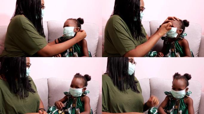 非裔美国人的母亲戴着面具给女儿戴口罩，以保护他们在家中免受细菌和COVIC 19的侵害
