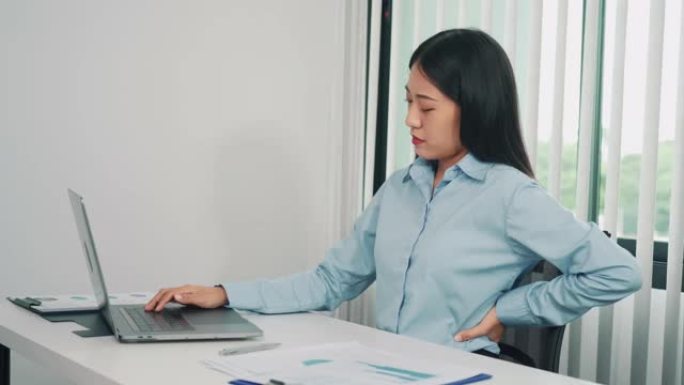 长期坐在工作岗位上的亚洲女性在按摩双手时背部疼痛。