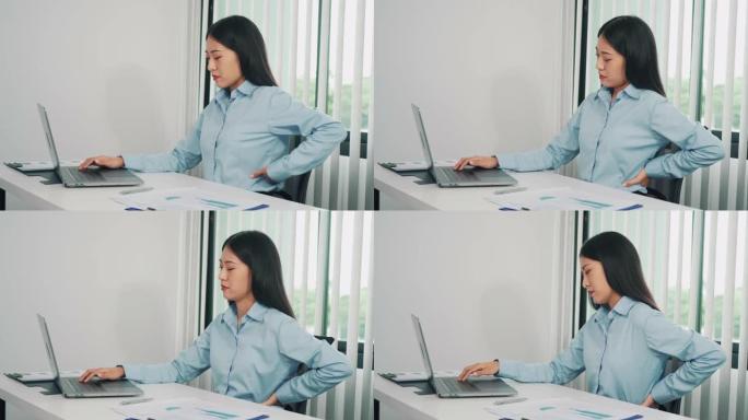 长期坐在工作岗位上的亚洲女性在按摩双手时背部疼痛。