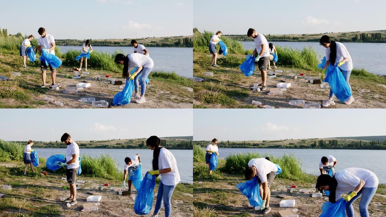 摄像机的特写镜头多种族的志愿者开始清理垃圾，他们在海滩边和湖边的蓝色塑料袋上收集垃圾。在阿里·阿列克