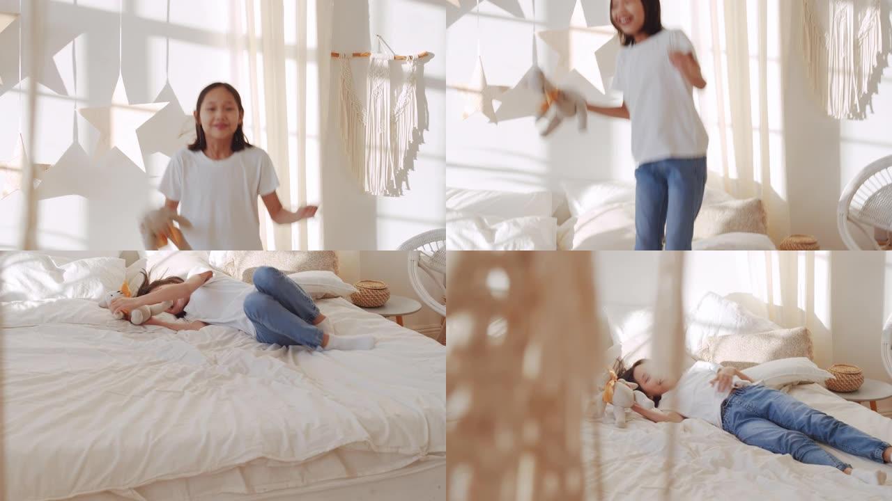 快乐的亚洲女孩在床上跳跃和摔倒