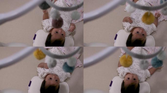 4k亚洲黑发婴儿婴儿躺在家里，用粉红色的毯子躺着，相机通过塑料天花板移动悬挂，头顶拍摄，卧室，儿童保