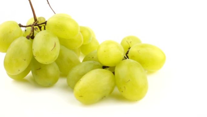 新鲜一束多汁的葡萄在白色背景上旋转。成熟多汁的葡萄在盘子上旋转。一串白葡萄的特写。