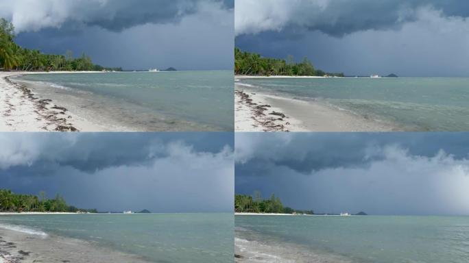 泰国湿雨季，苏梅岛沙质海岸挥舞着蓝色的大海。异国热带海洋海滩上的飓风和风暴警告。快速的风和不祥的云。