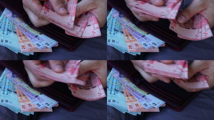 一个穿着商务衬衫的男人数着玻利维亚的钱。手里和钱包里有很多不同的钞票