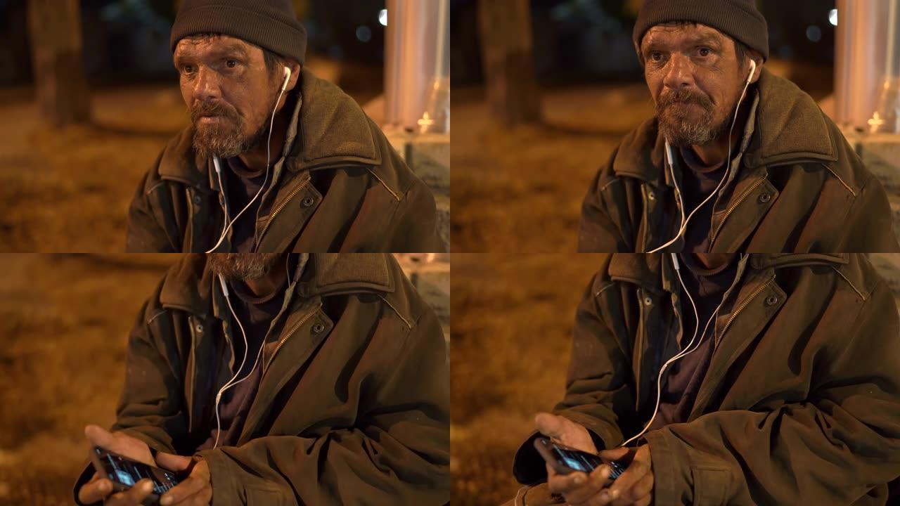 晚上在街上戴耳机的孤独寒冷的无家可归者的脸。