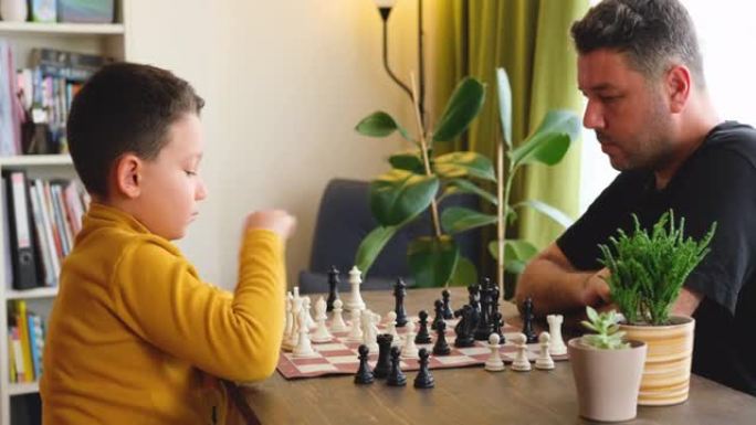 父子俩一起在家下棋。家里的家人。