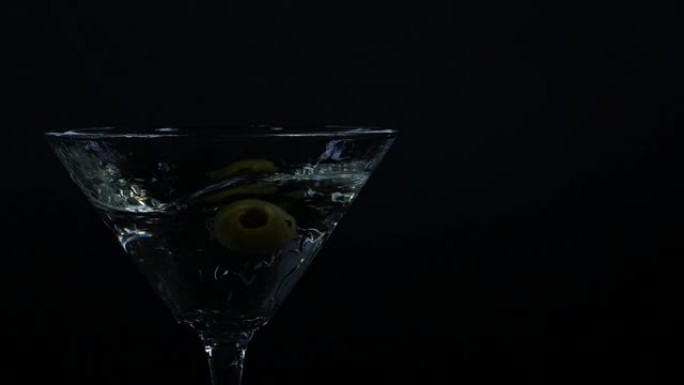 橄榄掉入一杯马提尼酒中的慢动作镜头