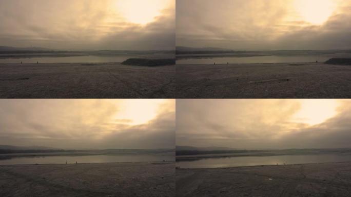 在英国南约克郡一个寒冷冰冷的冬季早晨日出期间，航拍画面飞越一个仍然霜冻的湖泊和冰冻的草地
