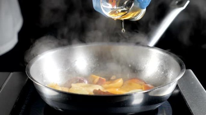 慢动作食物视频。Flamb é 风格的菜肴烹饪。特写。厨师将白兰地倒在水果煎锅上。厨师在餐厅做美味的