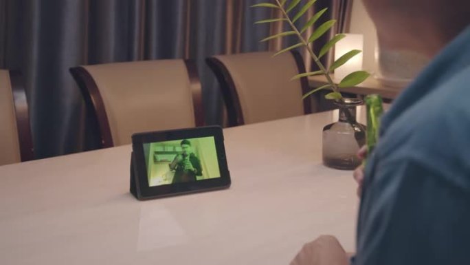 年轻的亚洲男子在家用平板电脑做派对视频通话时带着幸福
